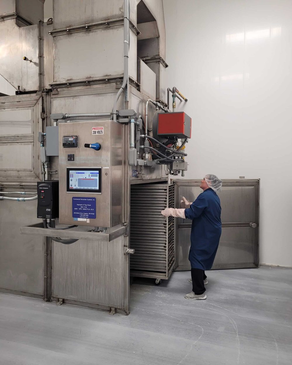 A technician at the dehydrator control panel at Entomo Farms