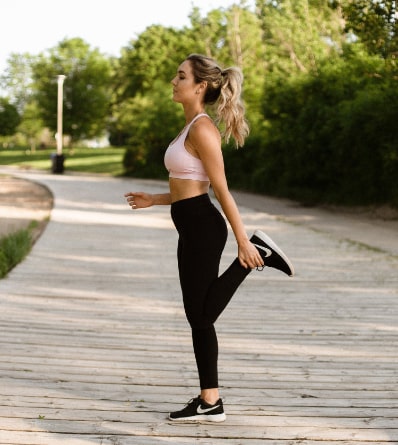 Photo of a young woman wearing exercise clothes, stretching before her workout.