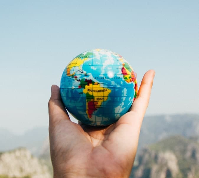 Photo of a hand holding up a small globe.